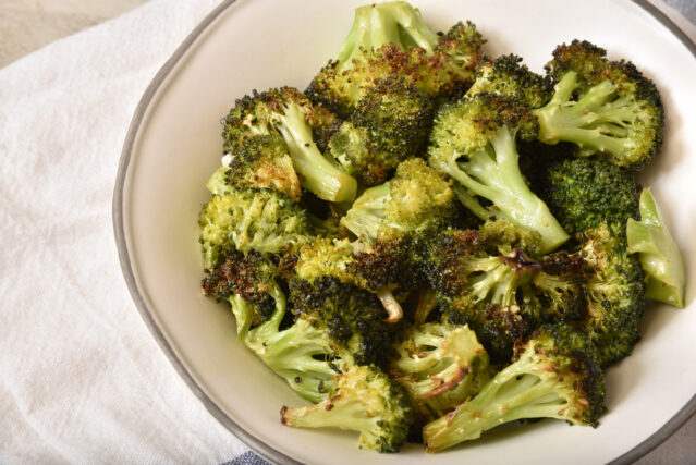 Overhead view of a bowl of roasted broccoli with garlic.