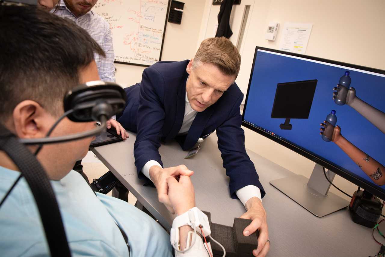 Chad Bouton (right) works in a lab at the Feinstein Institutes for Medical Research with Keith Thomas, a man living with paralysis.