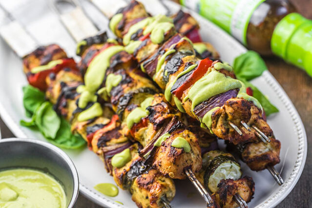 Italian chicken and veggie kabobs piled on a plate with Primal Kitchen Italian Vinaigrette.