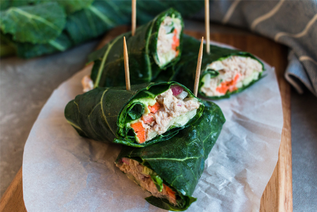 Tuna collard wraps skewered with toothpicks and piled on a plate.