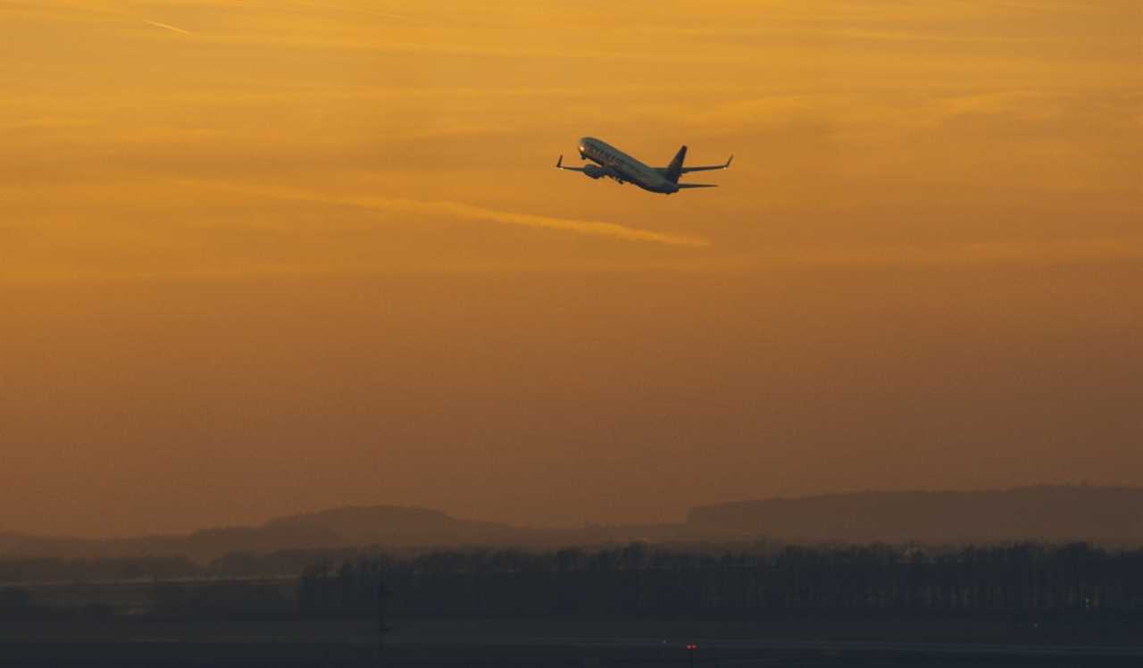 An airplane taking off during a bright orange sunset