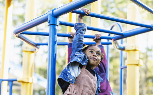 girl playing on playground monkey bars