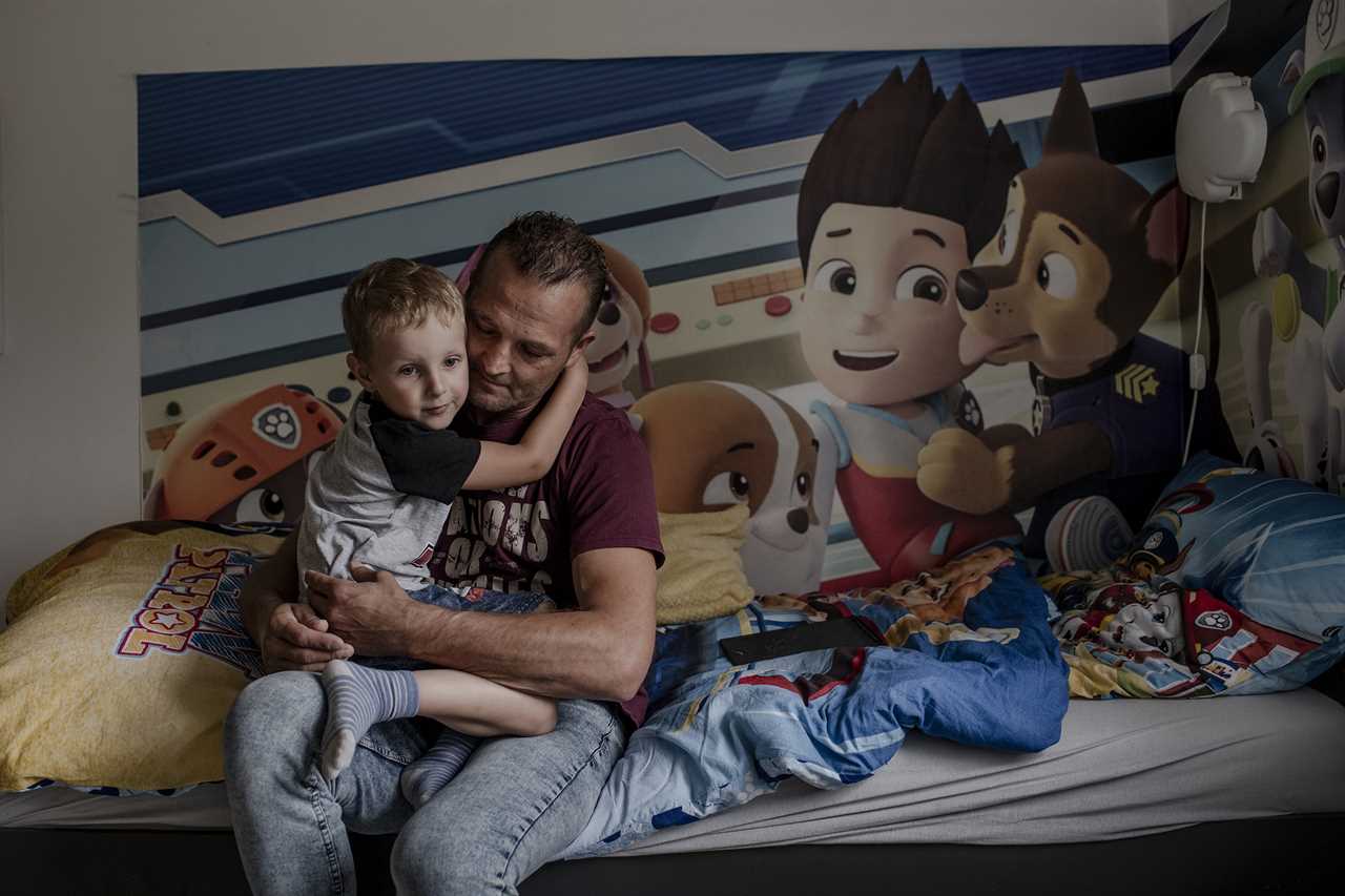 Janusz Kucharski holds his son Dawid in their home in Radoszowy, Poland, on July 30. 