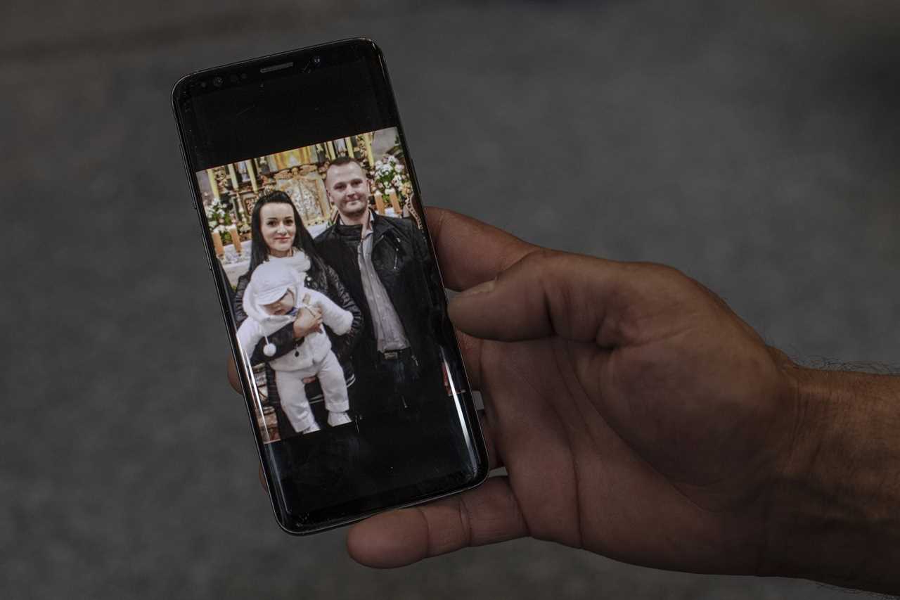 Janusz Kucharski shows a photo of Justyna and himself from the baptism of their son, Dawid.