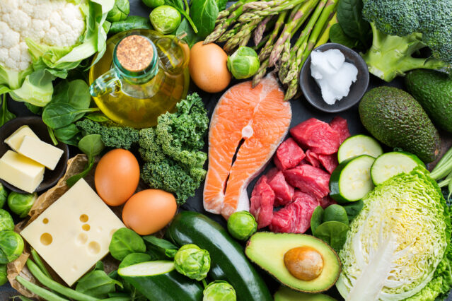 Array of green vegetables, eggs, cheese, salmon, red meat, avocado.