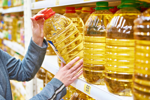 Large bottles of oil on grocery store shelf.