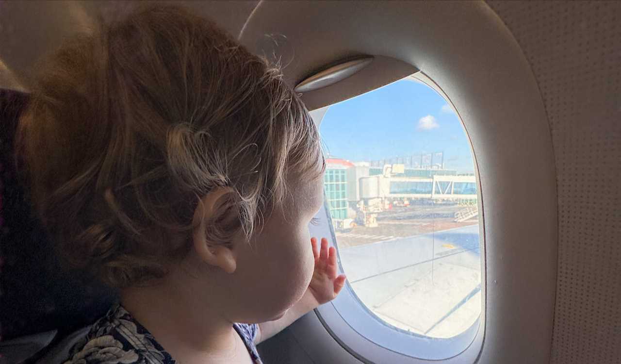 A young baby looking out a small airplane window