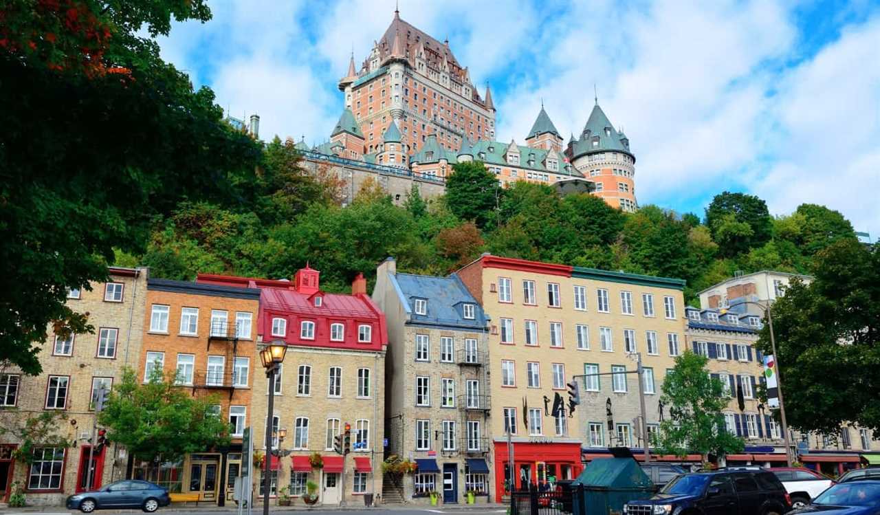 a row of stone houses with brightly colored roofs, as Frontenac Castle looms in the background of Vieux-Québec in Quebec City, Canada
