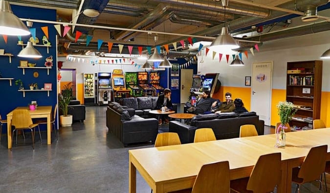 Festive common room at the CheapSleep Hostel in Helsinki, Finland, with people sitting and talking on black leather couches in the background and tables in the foreground