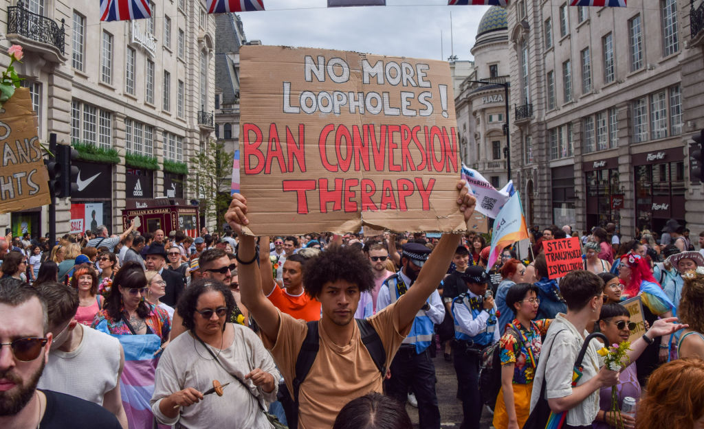 A protester holds a sign calling for a ban on conversion therapy.