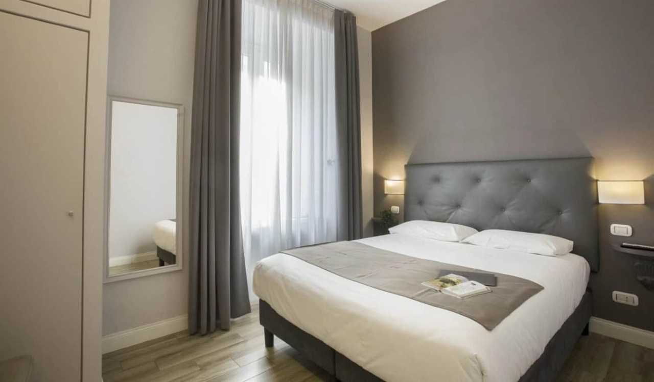 A simple grey guestroom at Colosseo Prestige Rooms in Rome, Italy