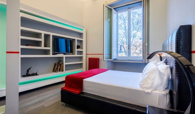 A simple guestroom with a bed opposite an entertainment center including shelves and a TV at Luxury on the River hotel in Rome, Italy