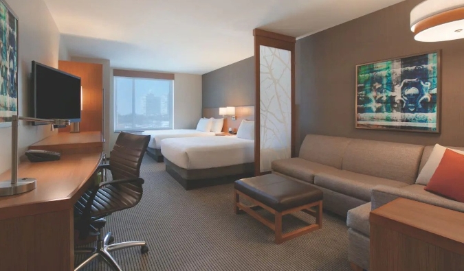 Guestroom at Hyatt Place Chicago South with two queen beds, a desk, and a large sectional couch