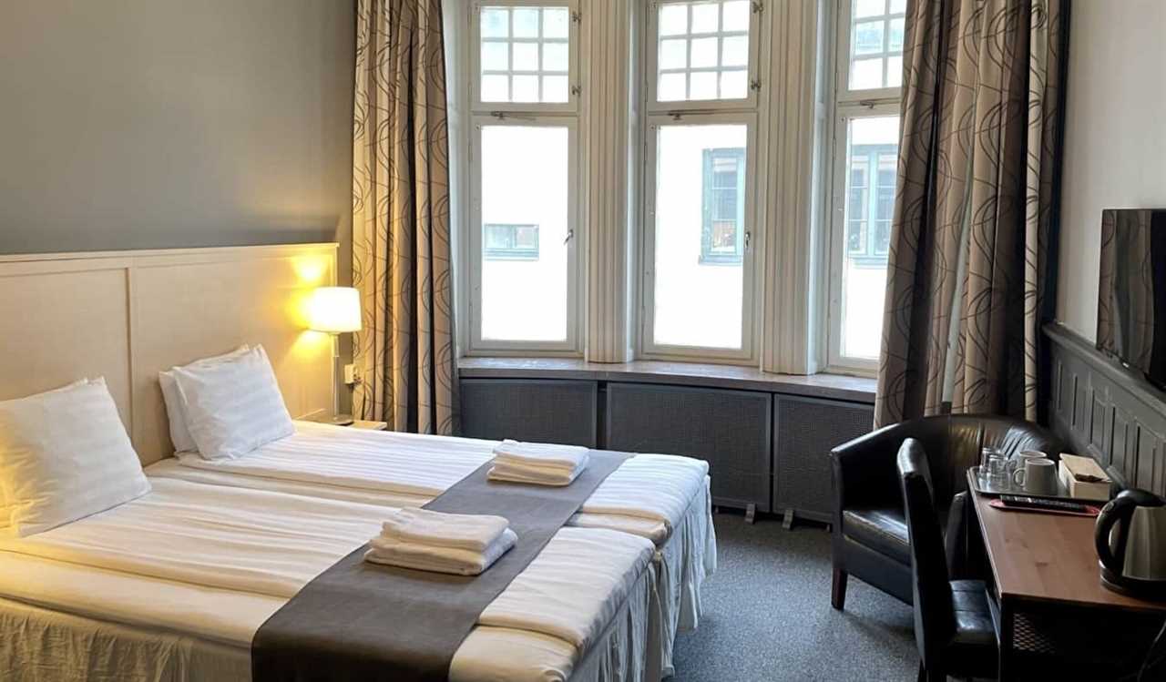 Simply decorated guestroom with a double bed and large windows at Unique Hotel in Stockholm, Sweden