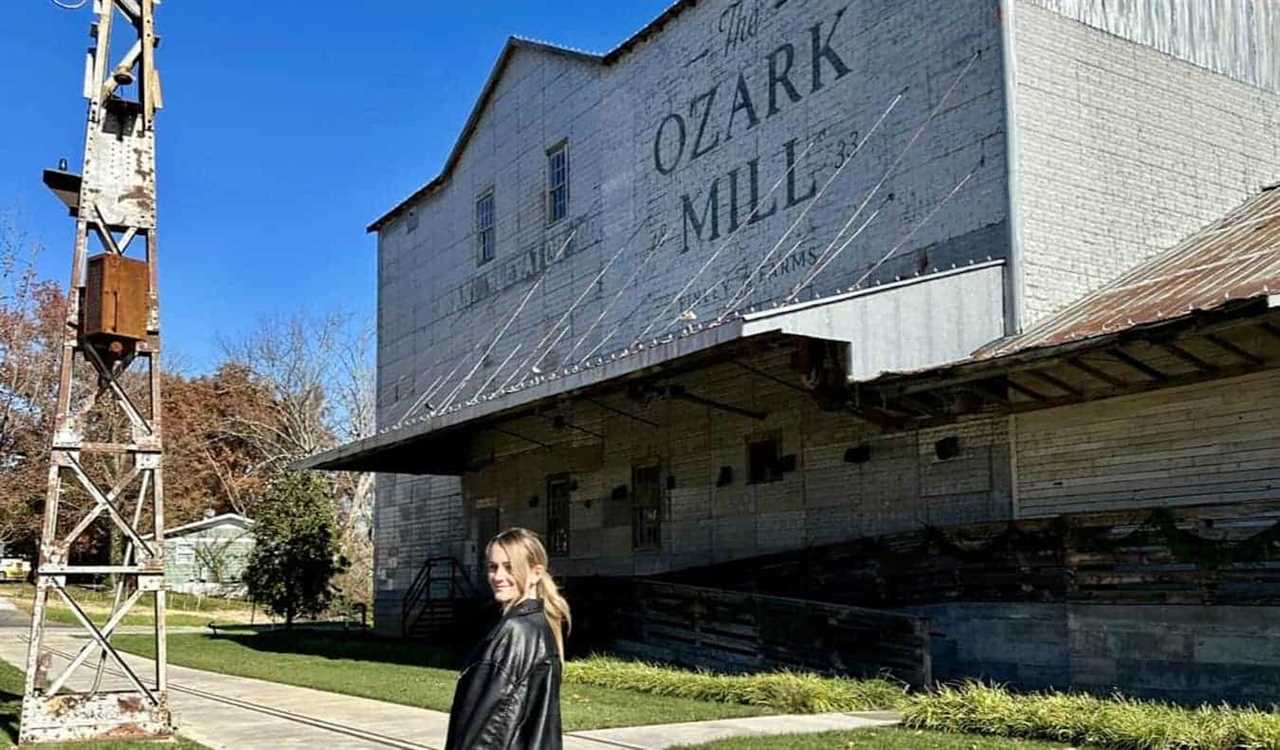 Travel blogger Raimee Iacofano posing near an old farm building on a Route 66 road trip in Missouri