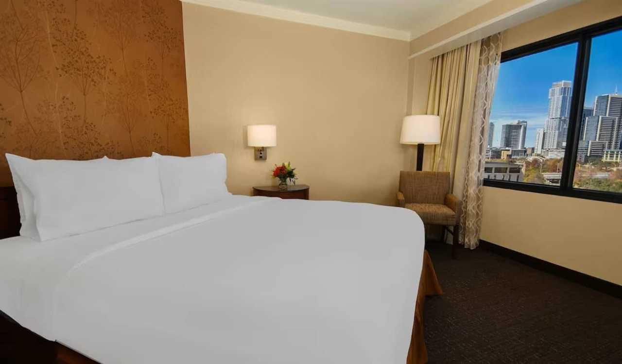 A simple guest room with a queen bed at Embassy Suites by Hilton in Austin, Texas