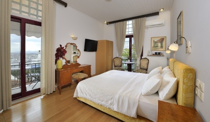 Homey guest room at Dryades and Orion Hotel in Athens, Greece, with a balcony opening out onto a view of the city