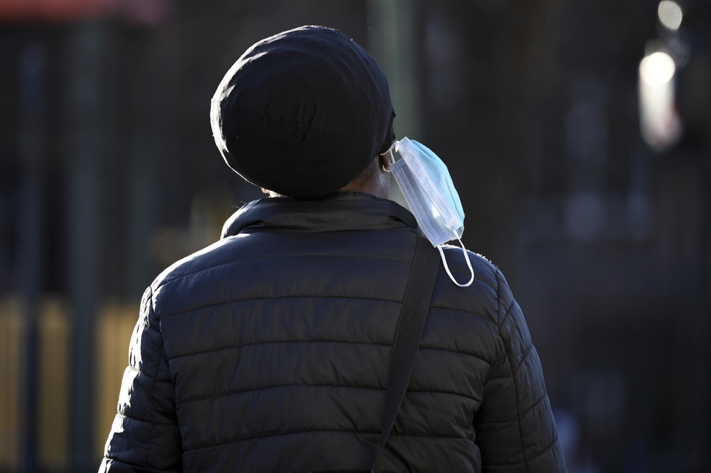 A person wears their mask dangling off an ear during the 2024 COVID-19 surge.