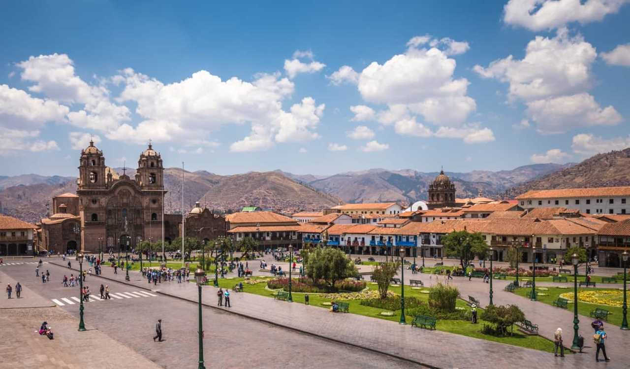 The sprawling Plaza de Armas with rolling mountains in the background in the historic center of Cusco, Peru