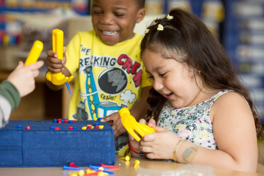 Preschool girl and boy hammering in a classroom