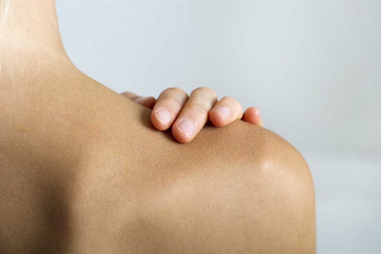 Woman with hand on bare shoulder, close-up TIME health stock