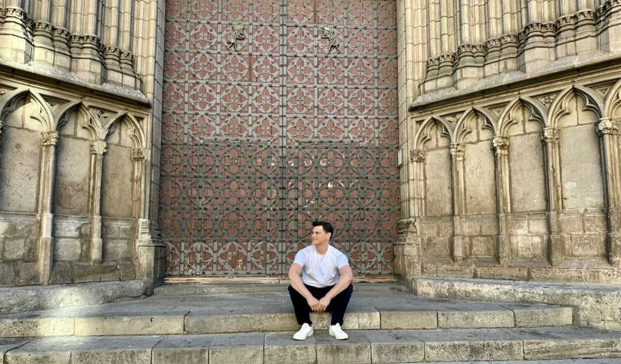 Nomadic Matt chilling on a wide, historic staircase in Spain during a sunny summer day