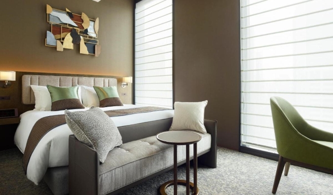 A hotel room with a double bed and two large windows with blinds drawn at The Celestine Ginza, a hotel in Tokyo, Japan