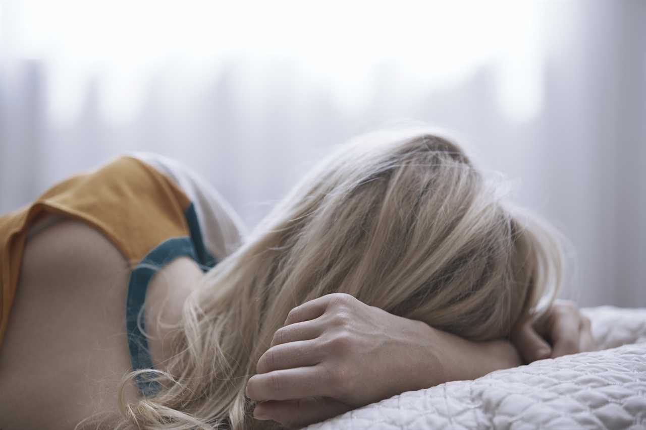 Blonde woman laying on bed TIME health stock