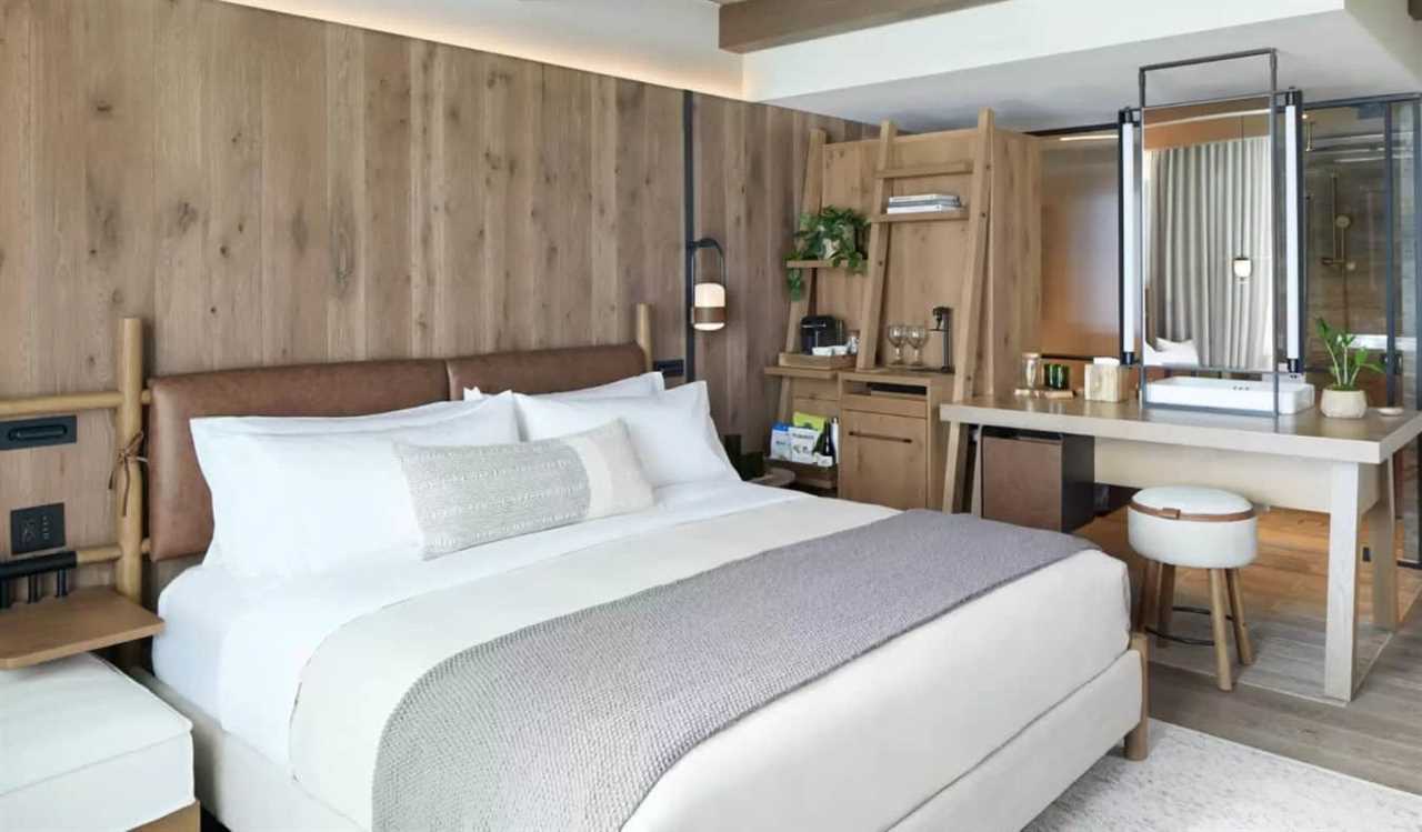 A king bed and vanity with a large mirror in a guest room with light wood-paneled walls at 1 Hotel in Nashville, TN