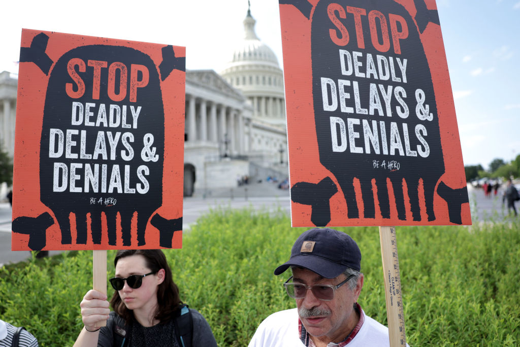 People holding signs protesting health insurance denials.