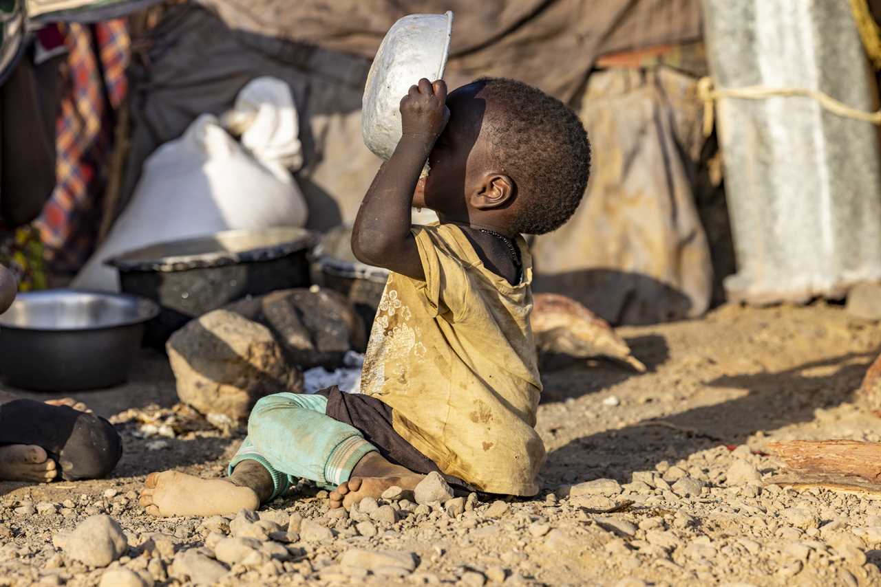 Close-up.Malnourished child due to extreme poverty, drought and climate change. Eating and drinking maize porridge in front of his dwelling. Kenya