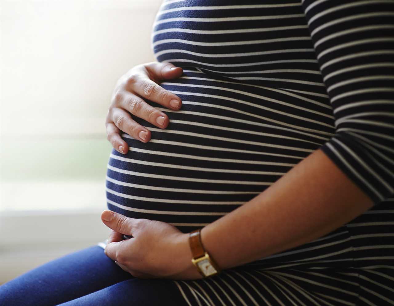 Heavily pregnant woman holding her bump