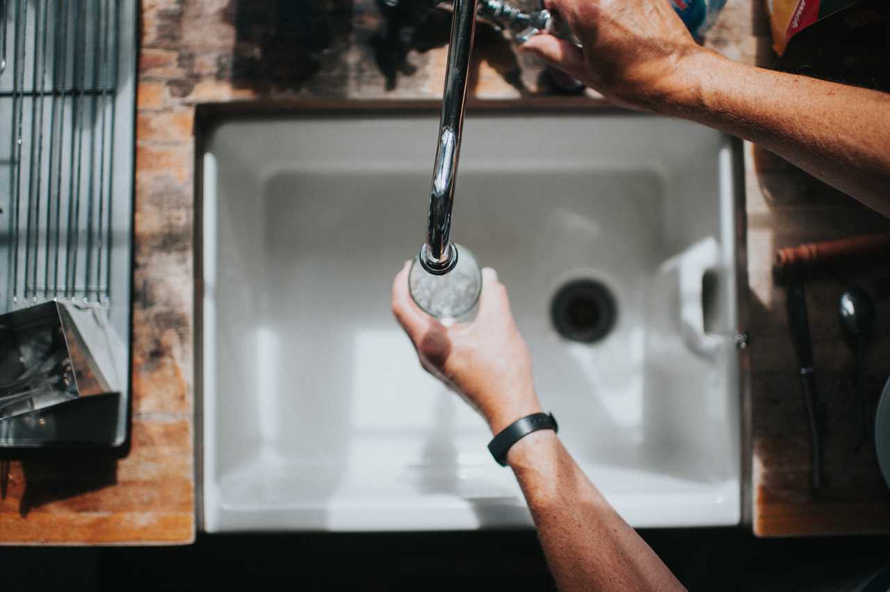 Someone fills a glass with tap water.