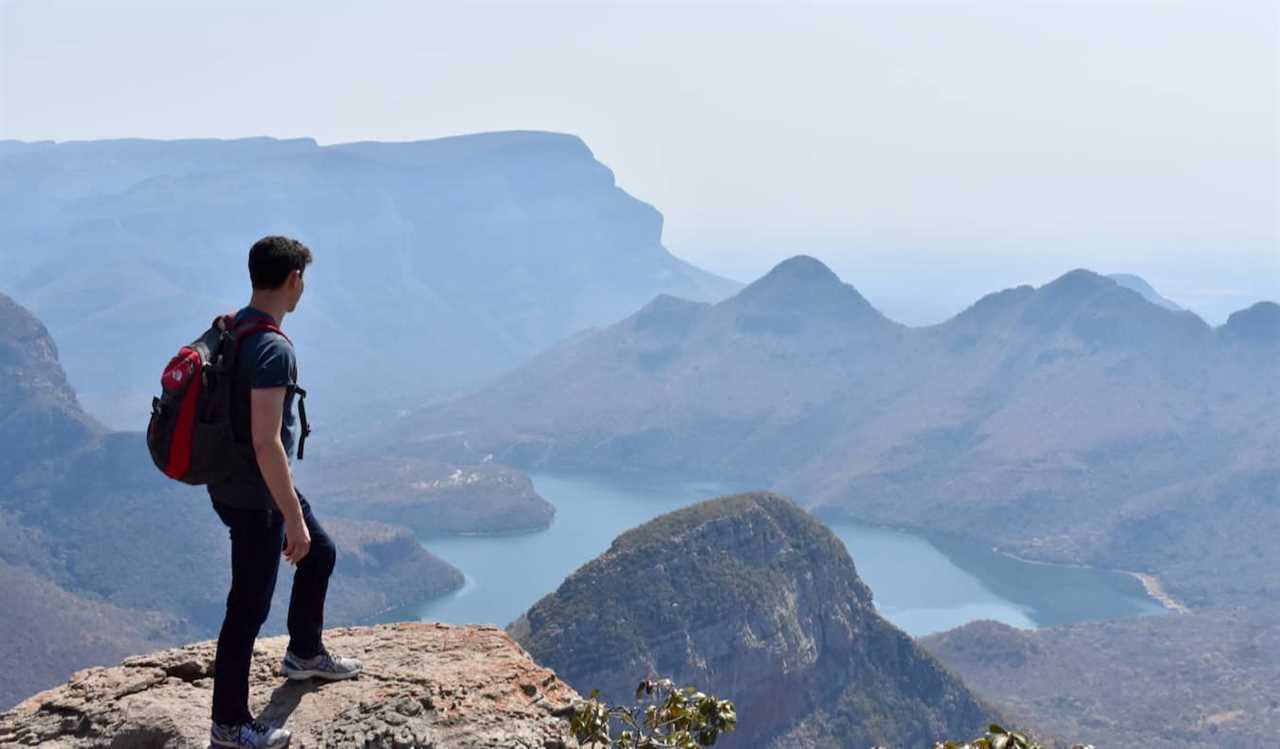 Nomadic Matt posing on a tall cliff while hiking in Africa