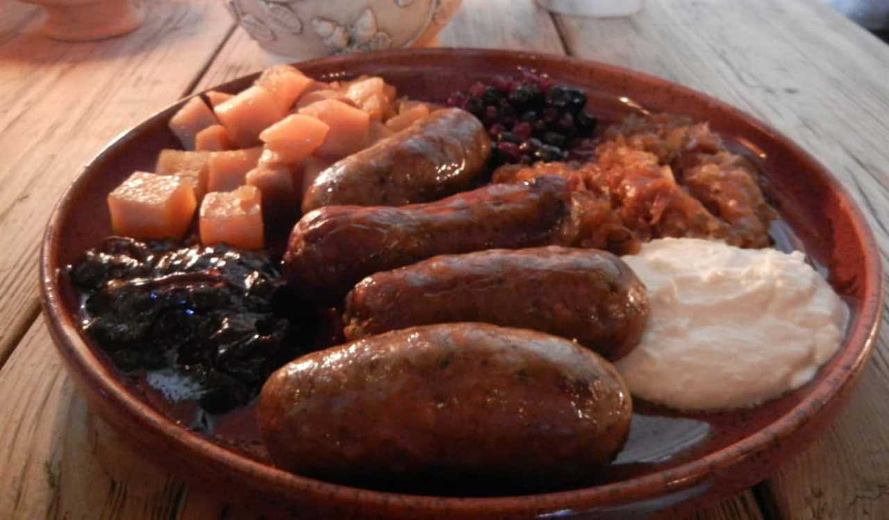 A breakfast plate of sausages, potatoes, and various dips