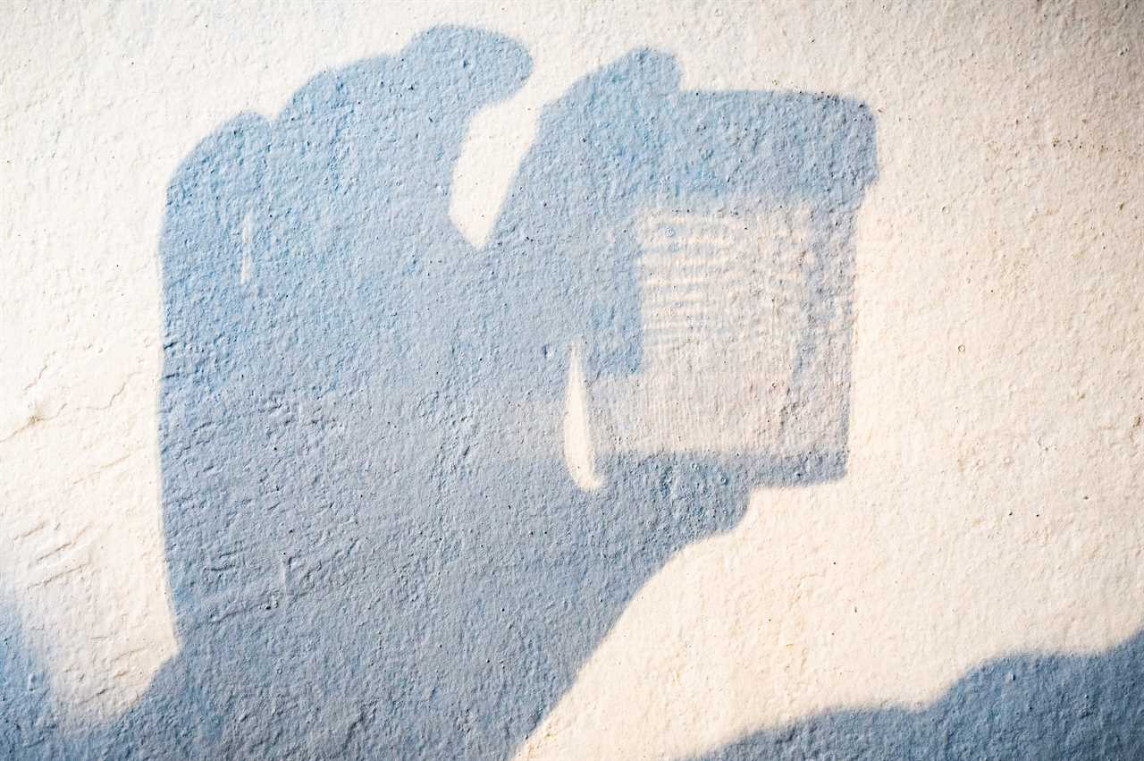 Shadow of someone holding in the hand a container to collect urine samples for laboratory analysis.