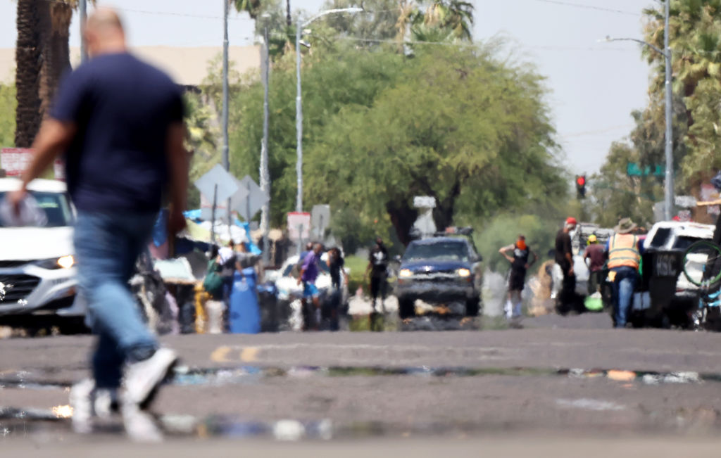 Heat waves shimmer, causing visual distortion, as people walk in the 'The Zone', Phoenix's largest homeless encampment, amid the city's worst heat wave on record on July 25, 2023 in Phoenix, Arizona.