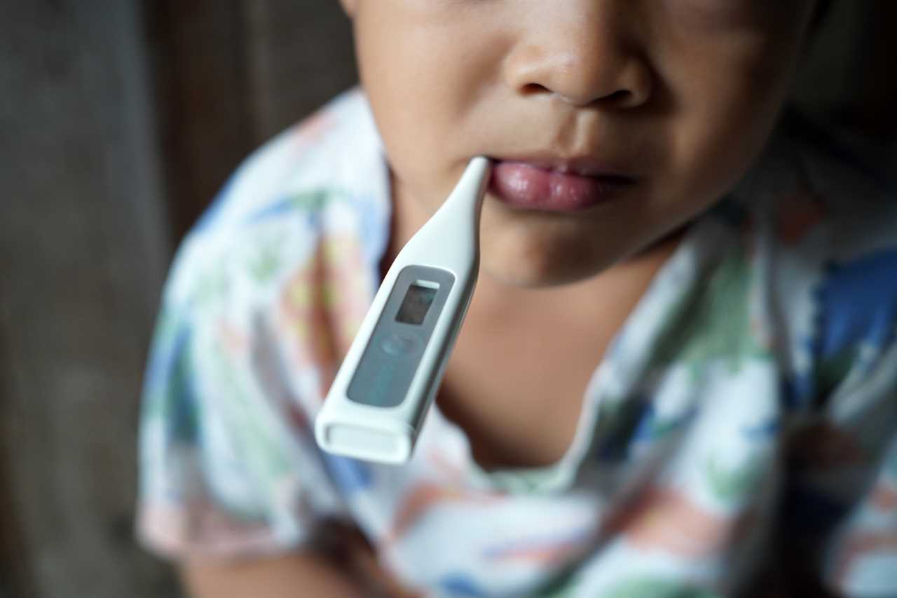 A sick child with a thermometer in his mouth